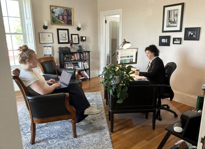 Two women sit in an office, holding a meeting