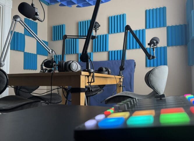 Sutherland-Weston's podcast room, a table is set up with four professional microphones and a soundmixing board with many colorful lights