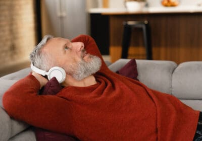A middle-aged man relaxes on the sofa, wearing headphones