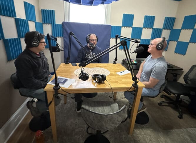 Ric Tyler and Dan Cashman chat with a guest in the podcast room